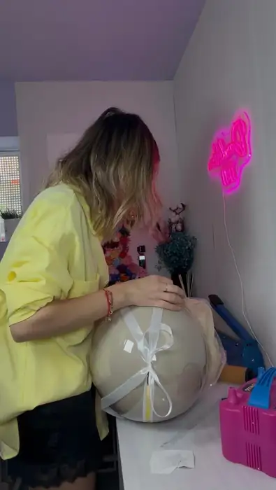 Raluca, Inhaberin von Dandelion 11:11, beim Fertigstellen eines großen Ballons mit weißer Schleife – liebevolle Detailarbeit für jede Kundenbestellung
